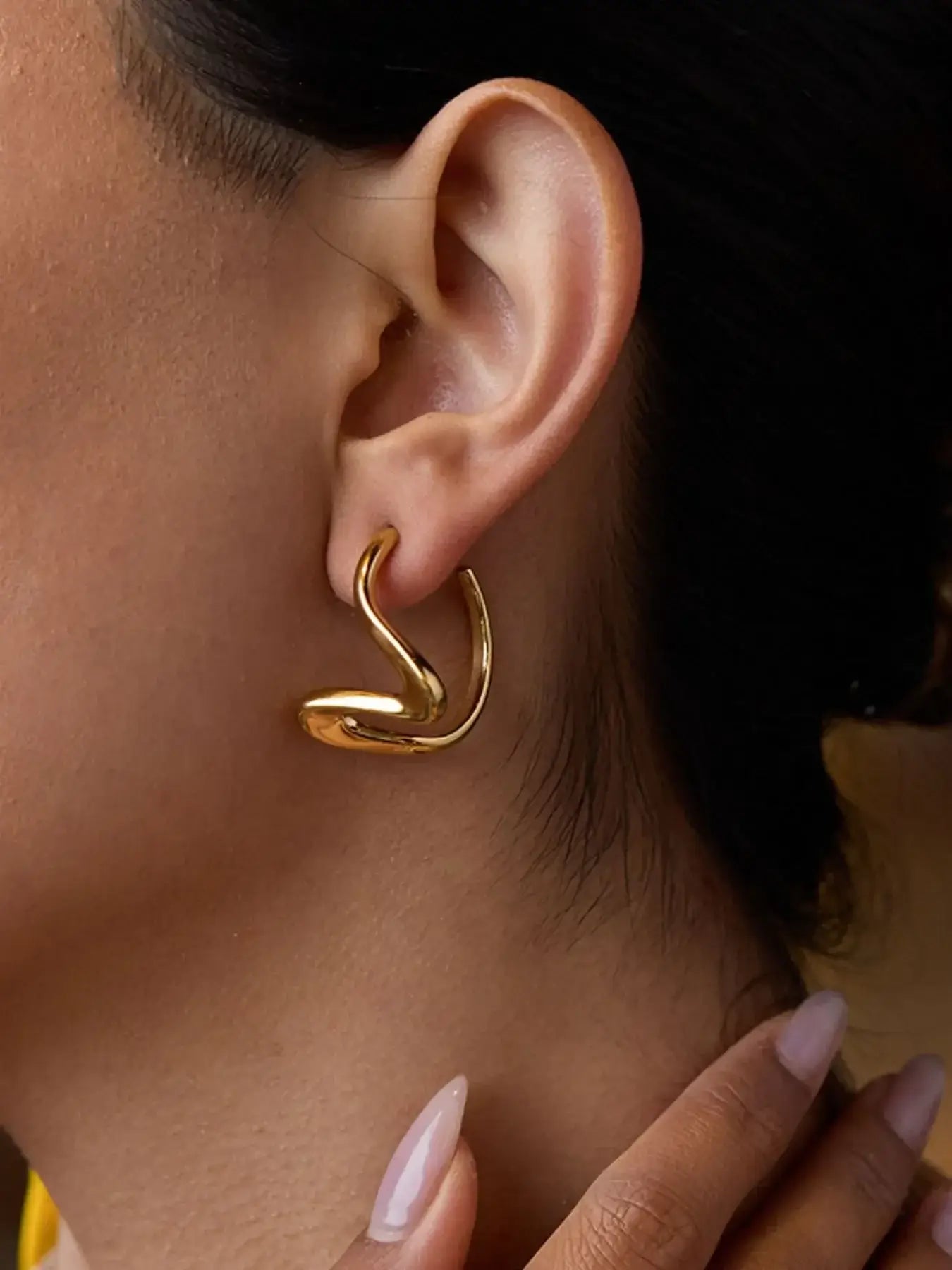 Elegant golden coil studs inspired by serpents, plated in 18K gold, curving softly along the lobe.